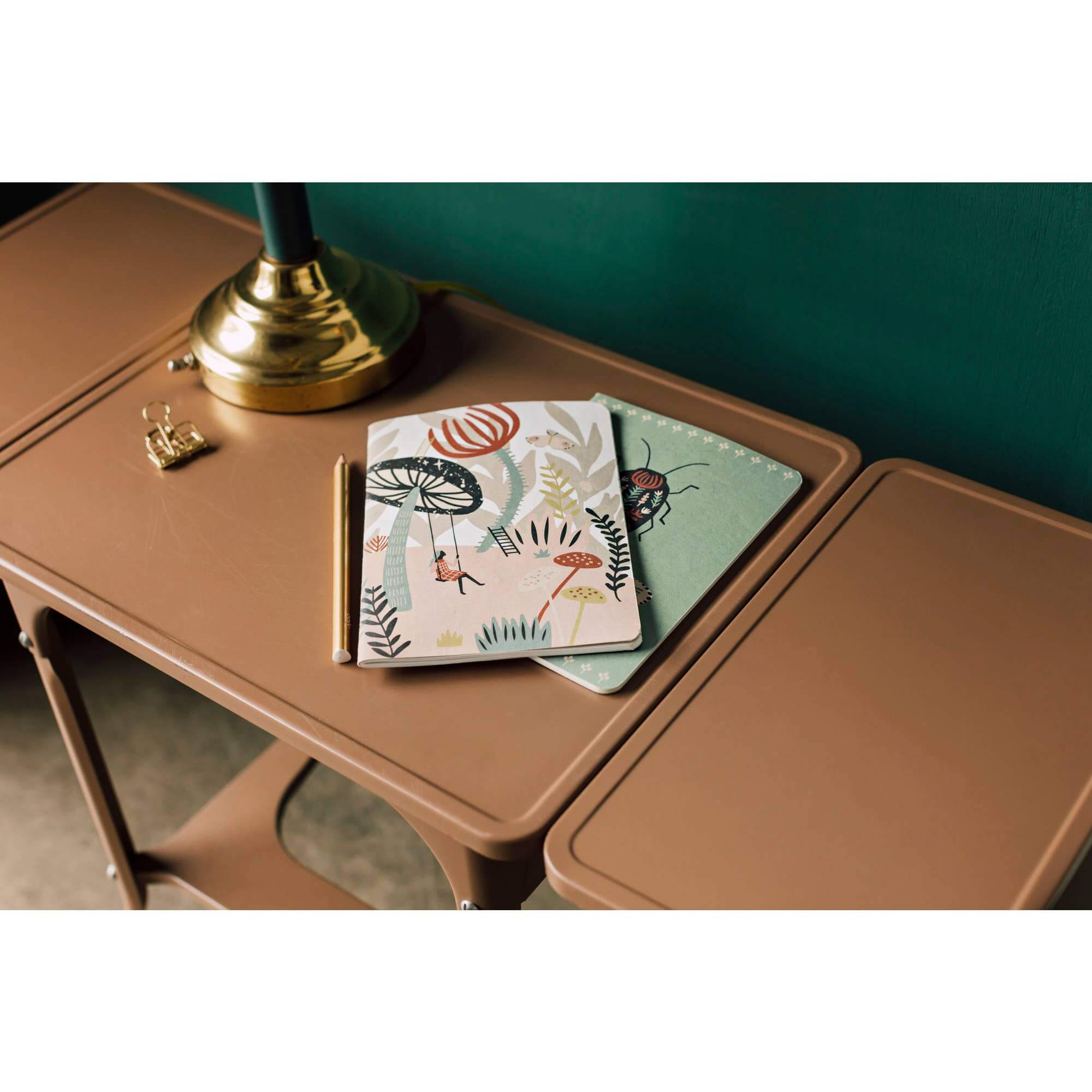 Danica Studio Far and Away Notebooks set on a stylish brown table with a lamp and decorative accessories.