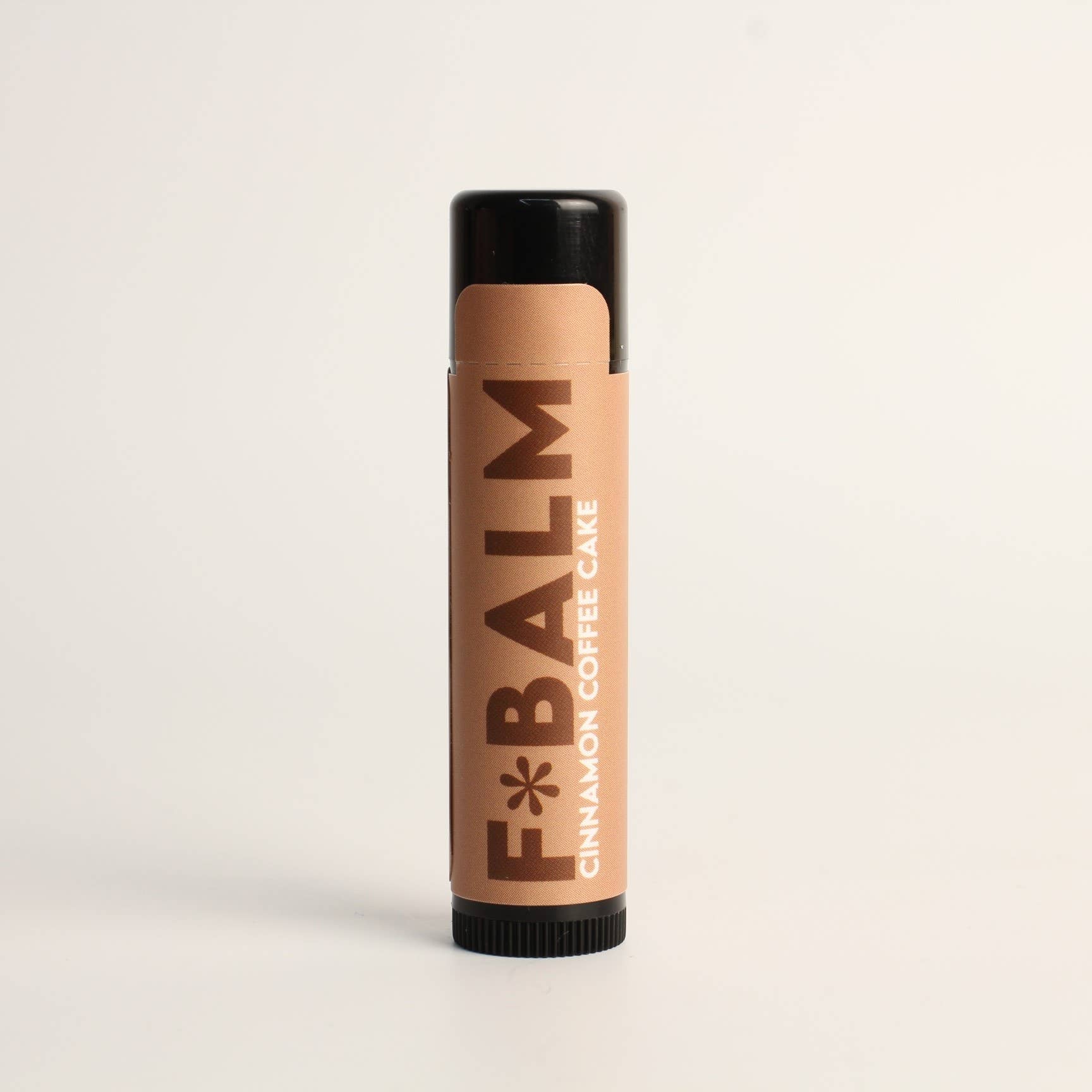F*Balm Cinnamon Coffee Cake Lip Balm in a sleek tube packaging, perfect for moisturized lips with a delicious flavor.