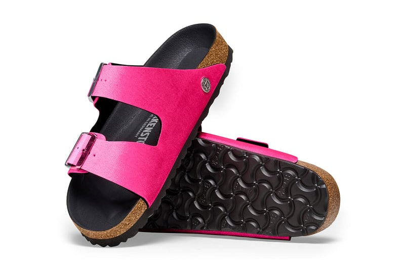 Birkenstock Women's Arizona Sandals in bright pink with rivet buckles and smooth black footbed, top view.