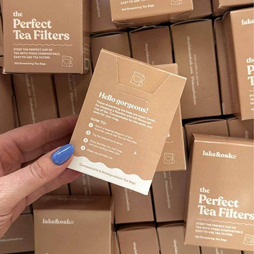 Person holding a package of lake&Oak tea filters with more packages in the background.