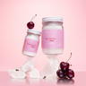 Bing Cherries + Clove Bath Soak jars with cherries on pink background, showcasing luxurious winter bath indulgence.