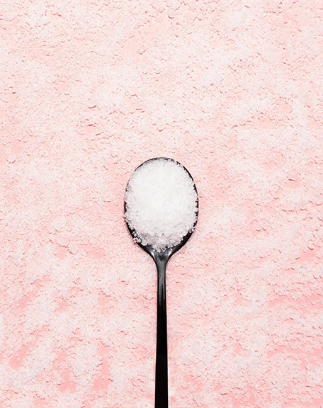 Bing Cherries + Clove Bath Soak jars with cherries on pink background, showcasing luxurious winter bath indulgence.