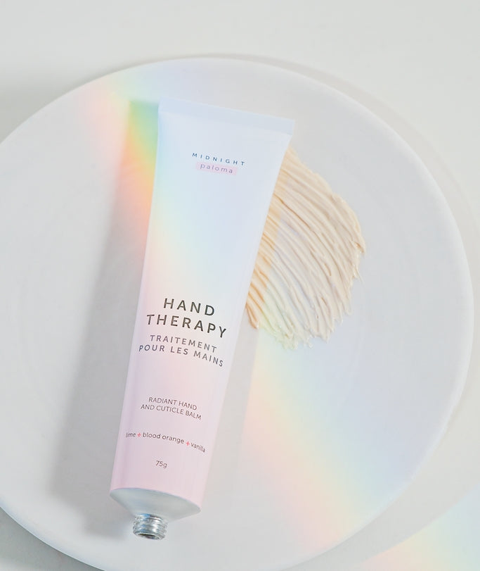 Hand Therapy Cream in a tube on a plate, featuring Blood Orange, Lime, Vanilla, and Grapefruit scents.