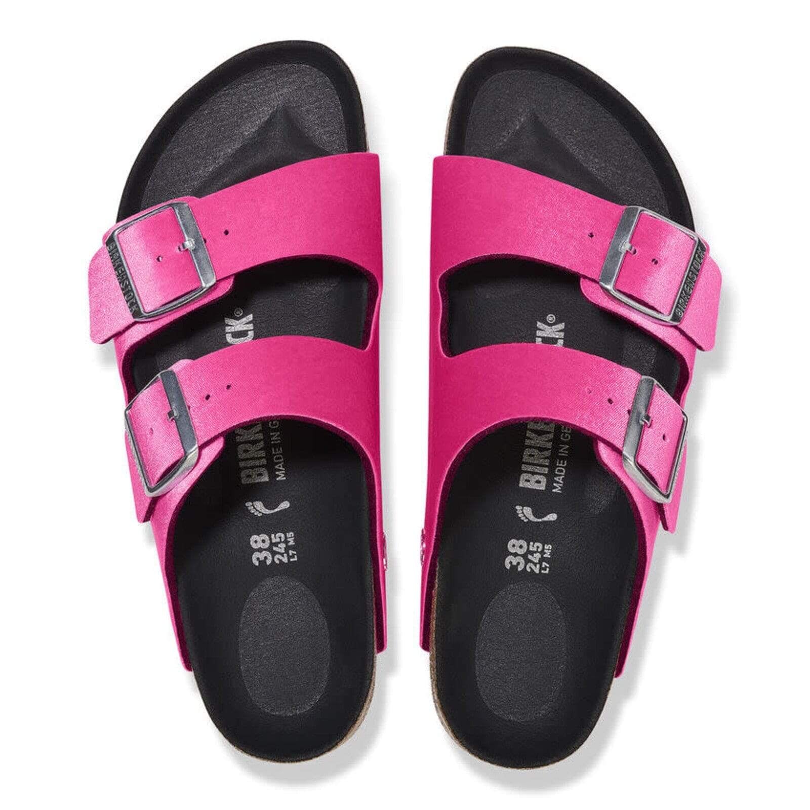 Birkenstock Women's Arizona Sandals in bright pink with rivet buckles and smooth black footbed, top view.