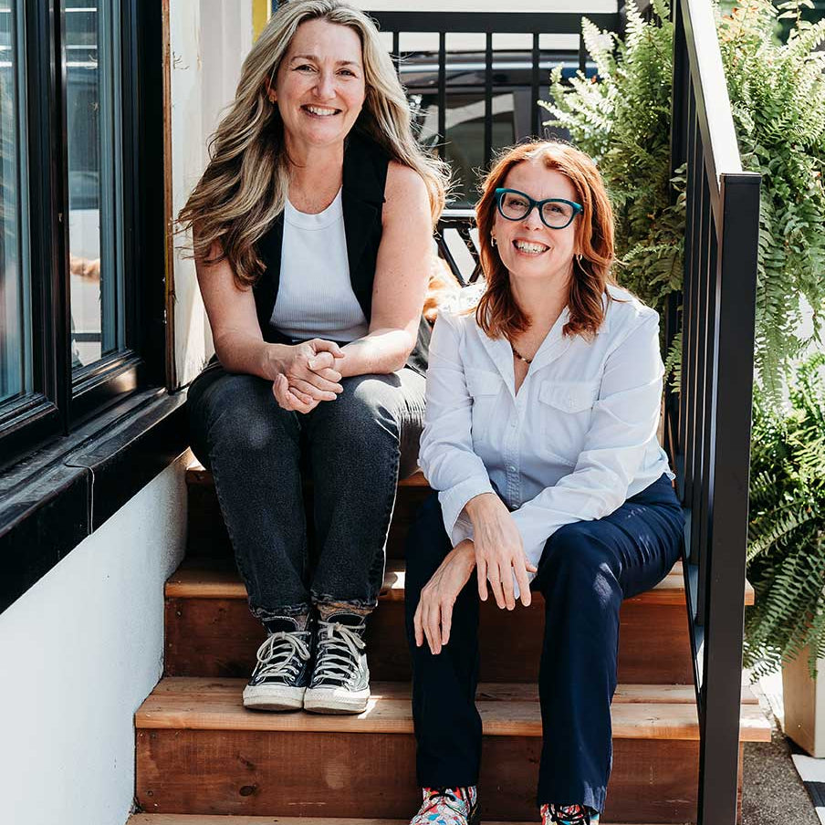 Margaret and Nancy sit on the front steps of M&N Apothecary
