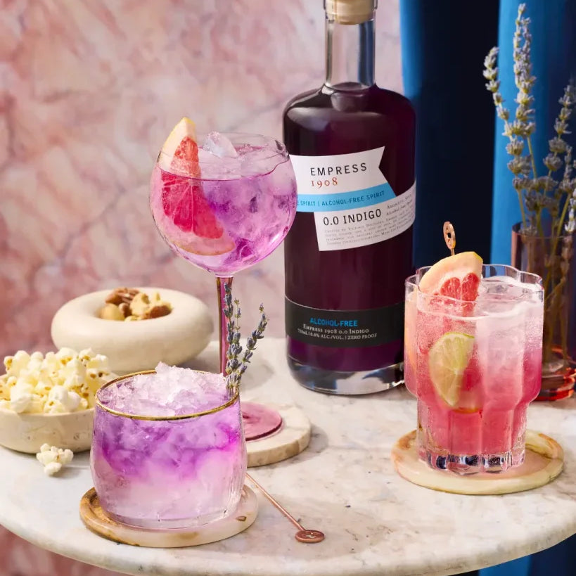 Cocktails with a bottle of Empress 1908 gin on a marble surface with a colorful background.  The Sobr Market