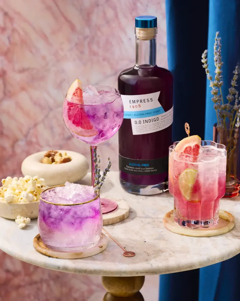 Cocktails with a bottle of Empress 1908 gin on a marble surface with a colorful background.  The Sobr Market