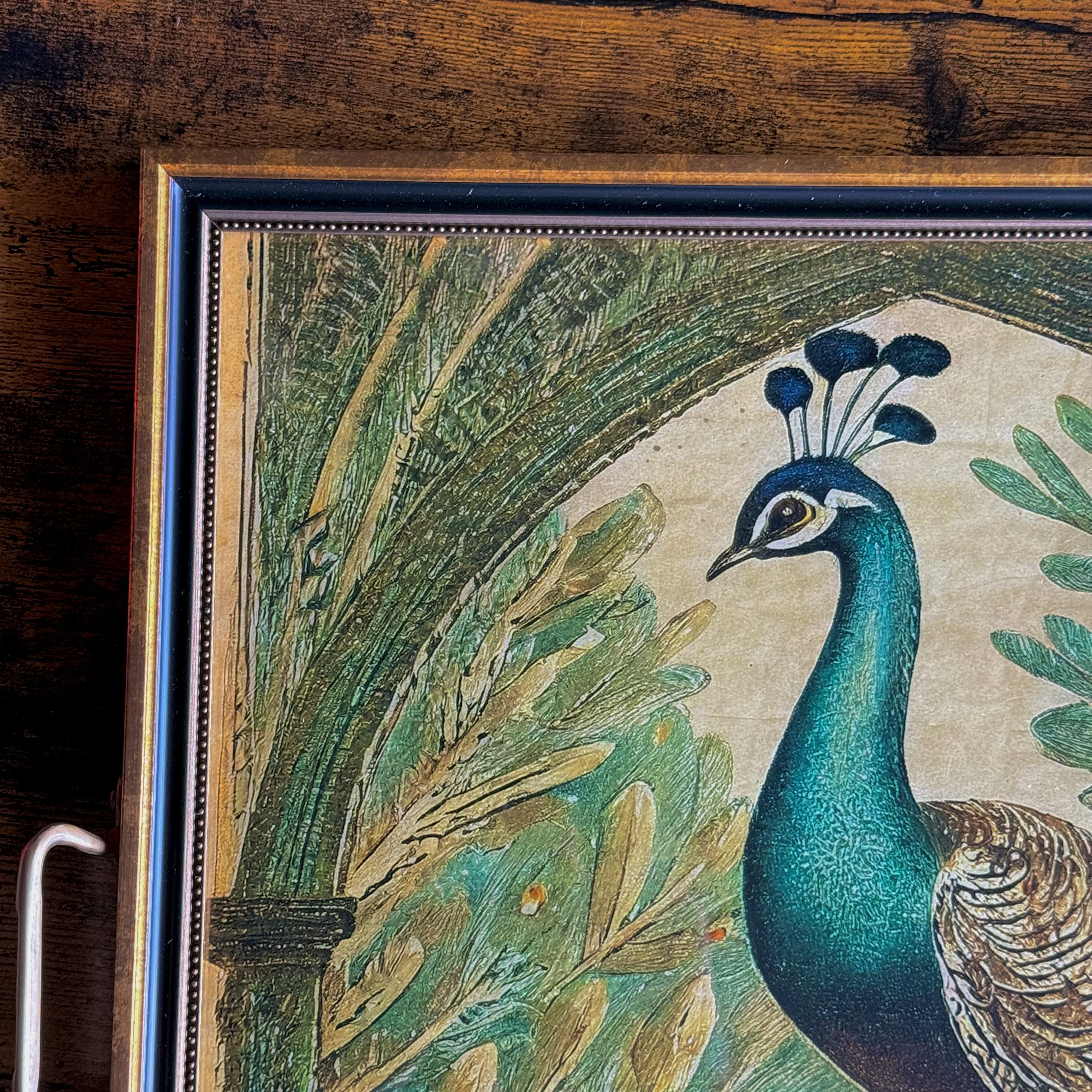 Framed artwork of a peacock among leaves on a wooden surface