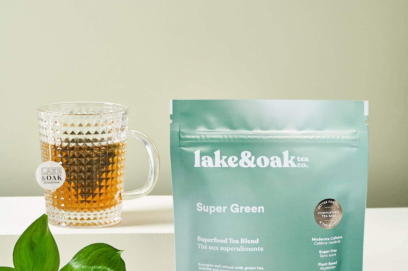 Lake & Oak Super Green tea blend with a cup, fresh lemon, and ingredients on a light background.