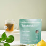 Lake & Oak Super Green tea blend with a cup, fresh lemon, and ingredients on a light background.