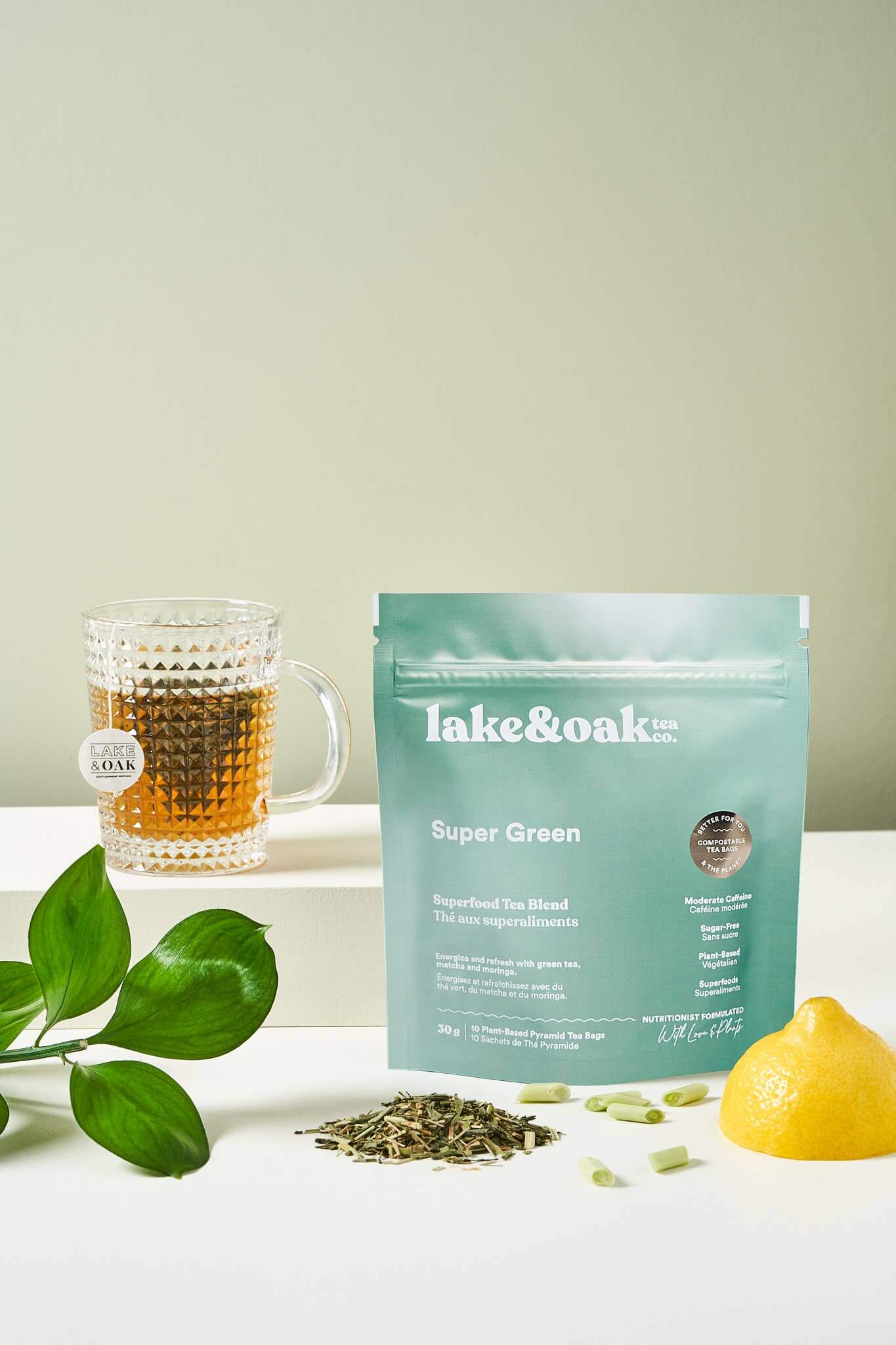 Lake & Oak Super Green tea blend with a cup, fresh lemon, and ingredients on a light background.