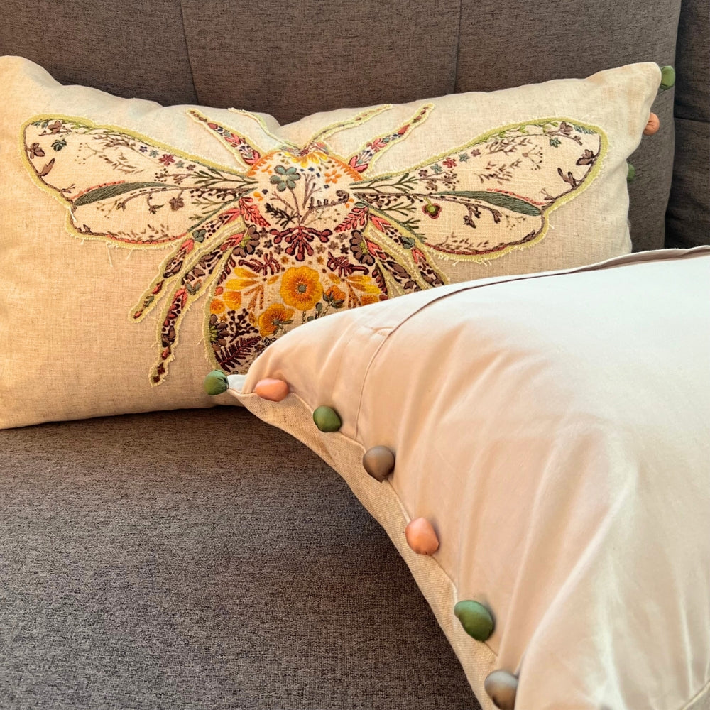 Decorative pillow with floral moth design on a textured surface