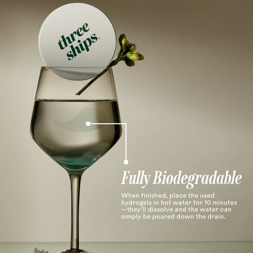 A biodegradable eye mask in a glass of water with a flower, showcasing its eco-friendly properties.