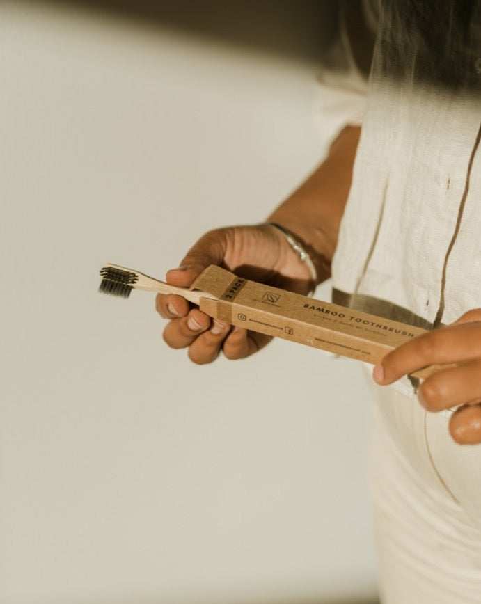 Person holding a bamboo toothbrush with packaging