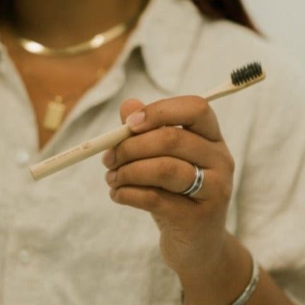 Person holding a bamboo toothbrush with black bristles