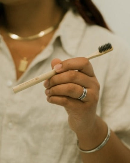 Person holding a bamboo toothbrush with black bristles