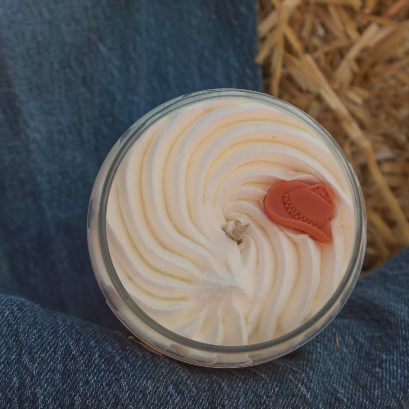 Close-up of a dessert with whipped cream and a cherry on top, placed on a blue fabric surface.