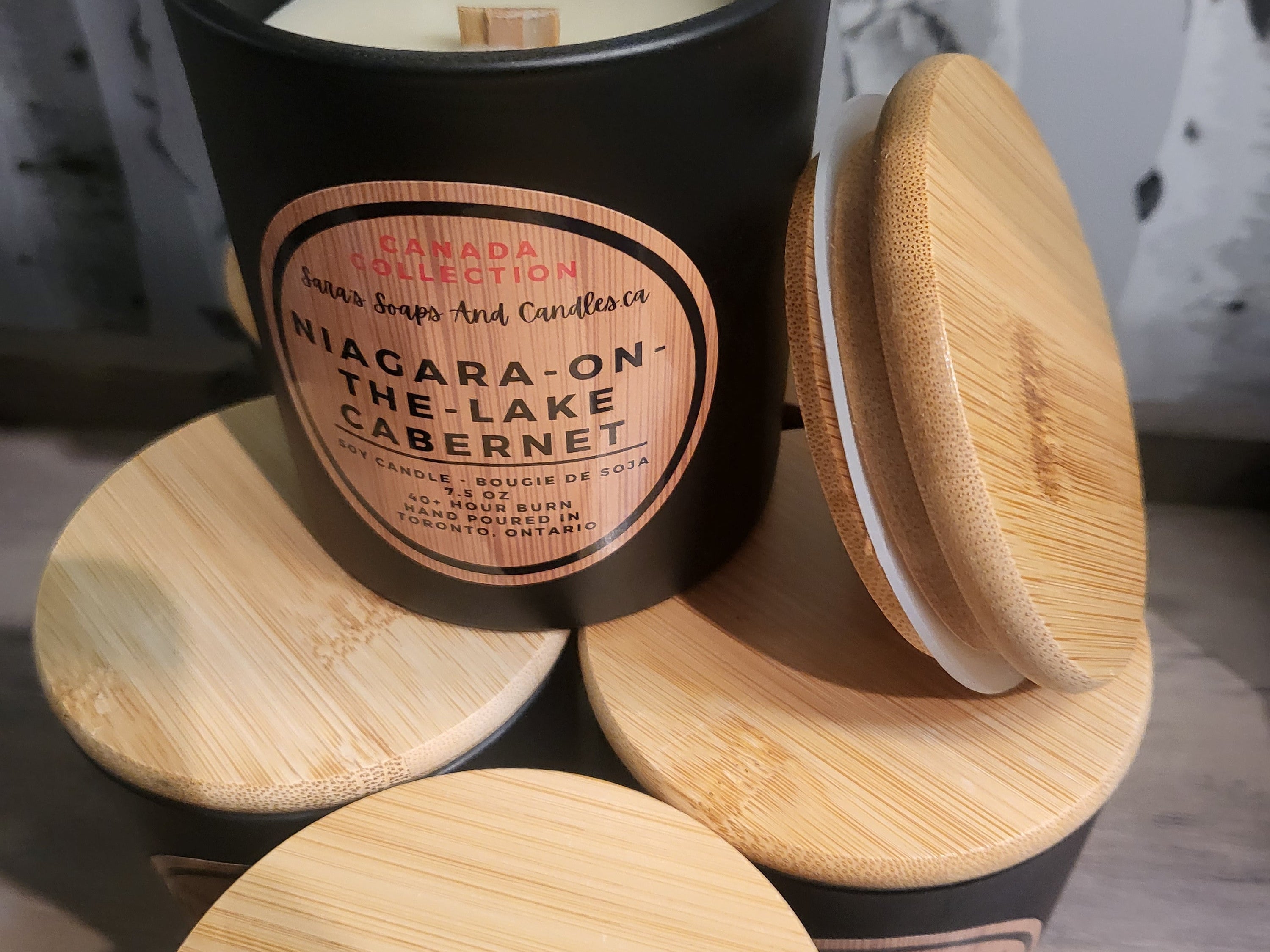 Candle in a black container with wooden lid on a wooden surface