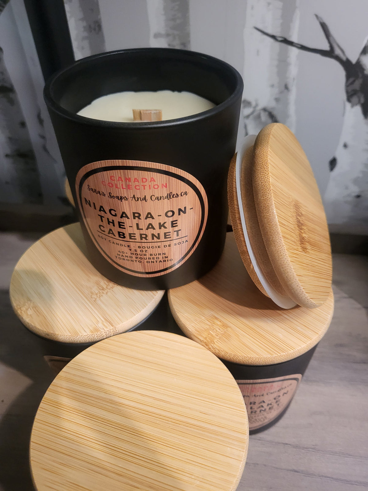 Candle in a black container with wooden lid on a wooden surface