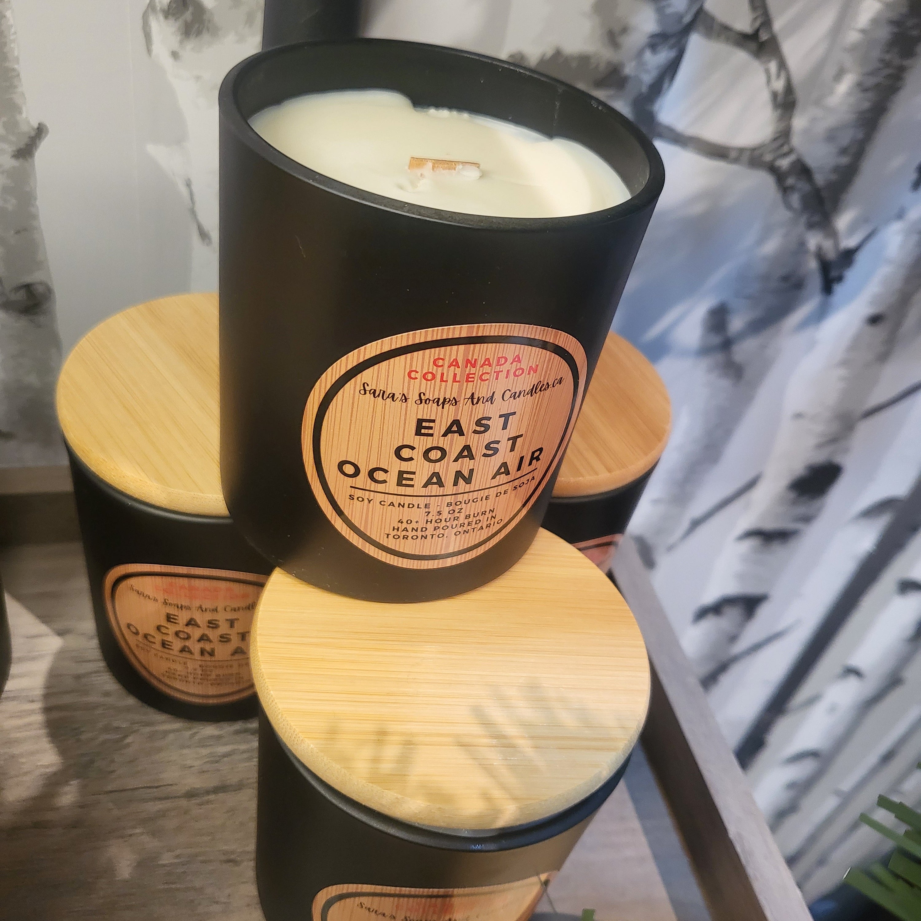 Black candle with wooden lid labeled 'East Coast Ocean Air' on a surface.