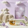 Chill Mama' by Lake & Oak superfood tea blend decaf with a cup of tea, knitted blanket, and toy on a light purple background.