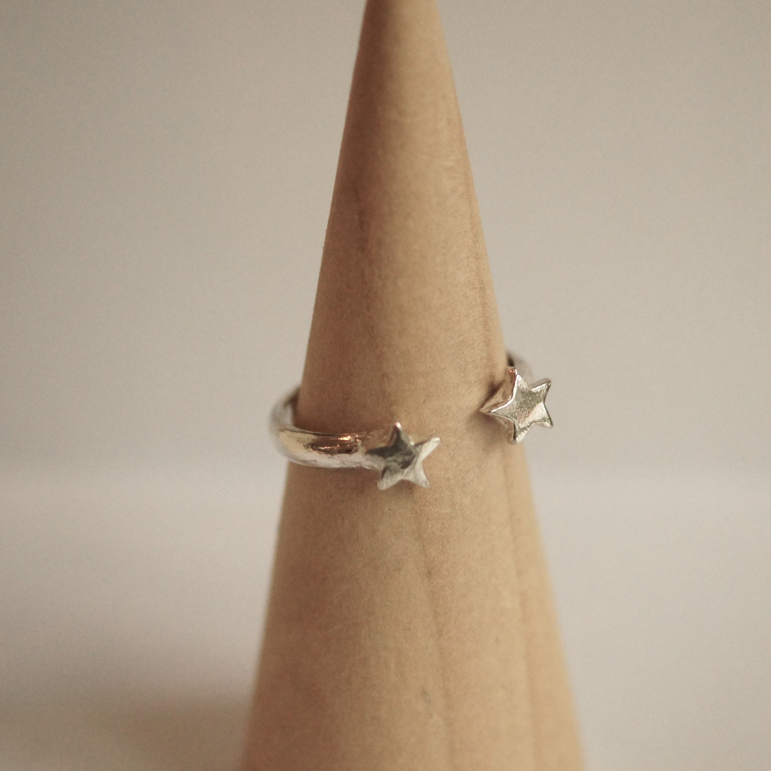 Silver star ring on a finger against a neutral background