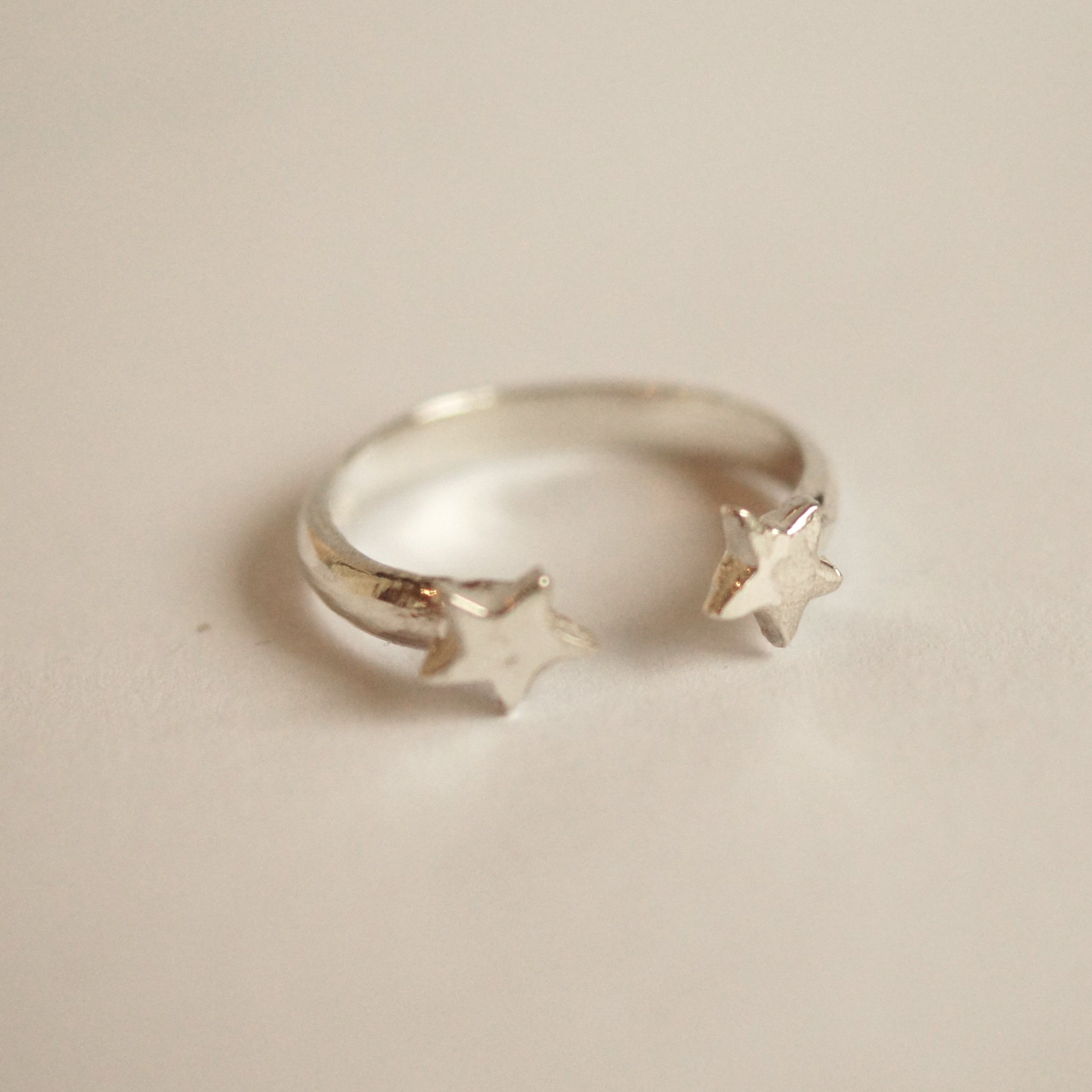 Silver ring with star designs on a beige background