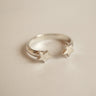 Silver ring with star designs on a beige background