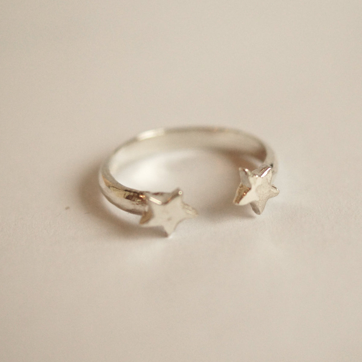 Silver ring with star designs on a beige background