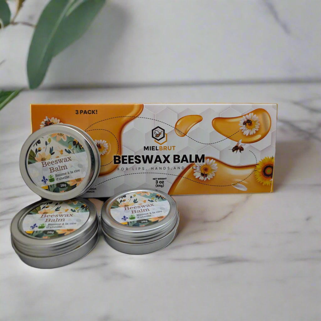 Three tins of Miel Brut Beeswax Balm with packaging on a marble surface.