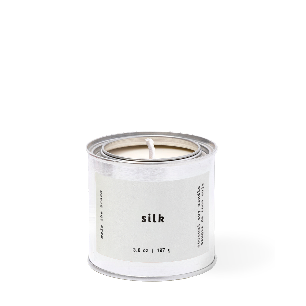 Candle in a white canister labeled 'silk' on a white background