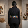 Person wearing a black blazer with a colorful belt in an art gallery setting