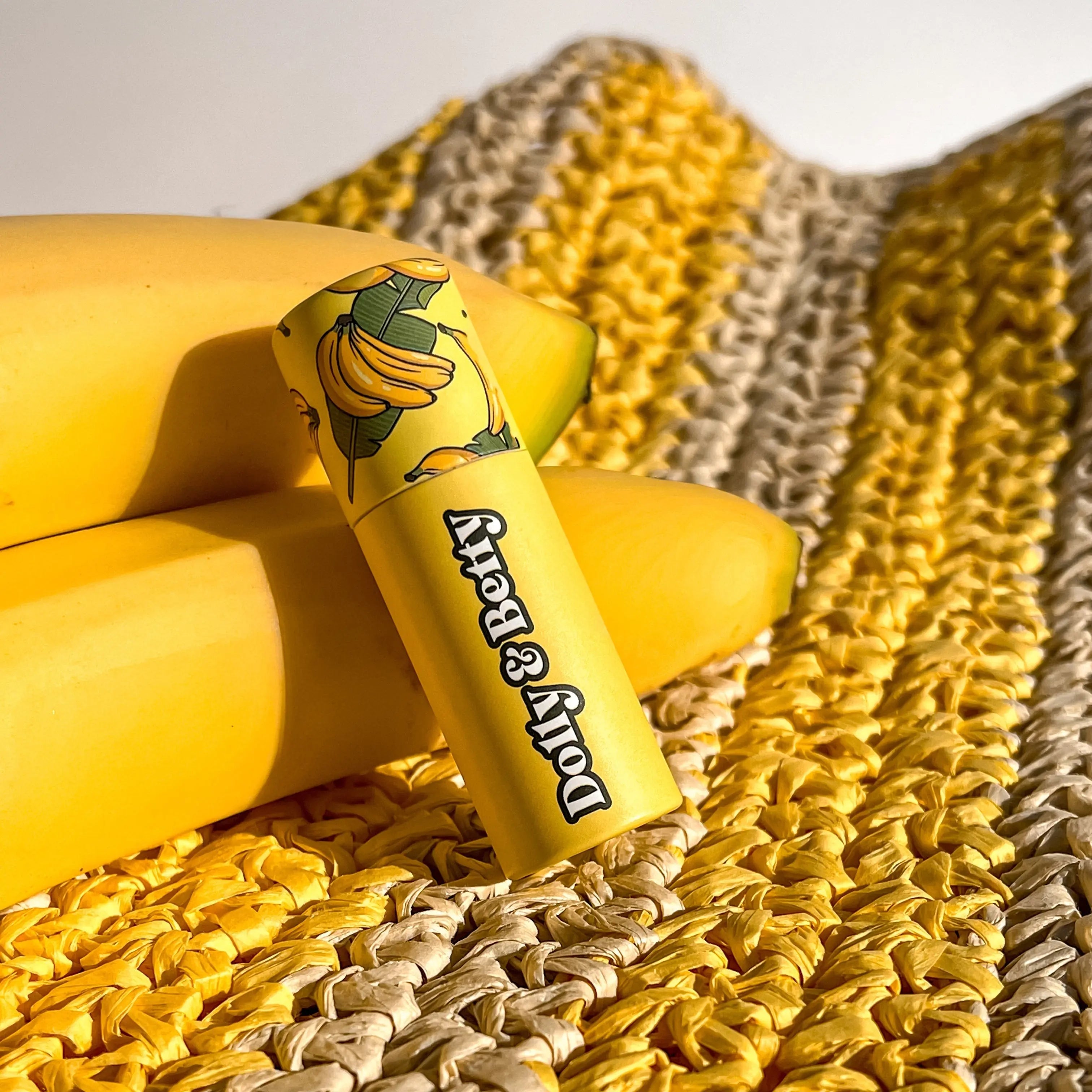 Yellow lip balm with banana design on a textured surface