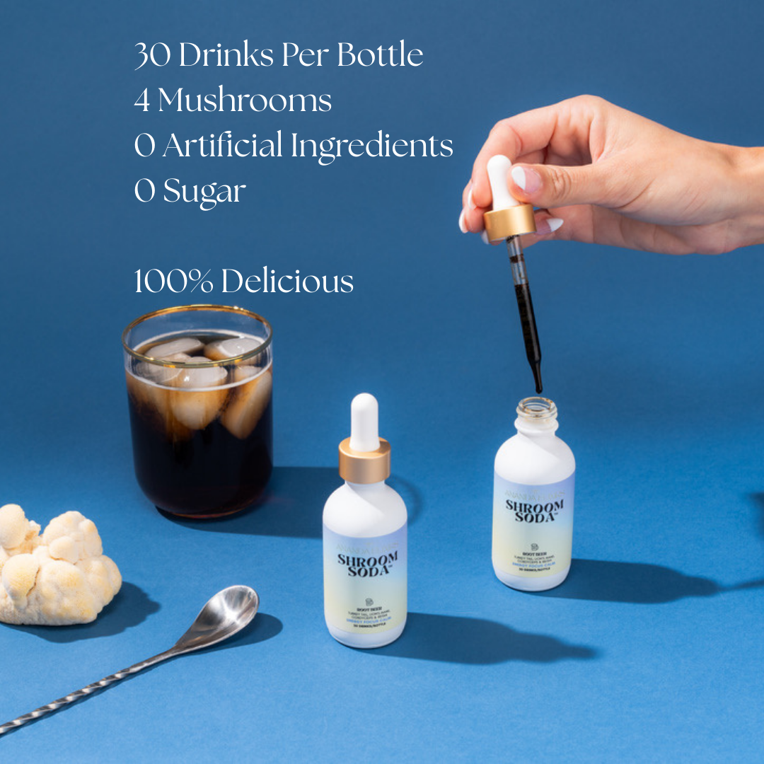 Hand using a dropper to add liquid from a mushroom-based product into a bottle on a blue background.