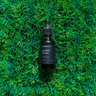 OC Beauty - Glossy Glow Hair Oil Black bottle on green grass