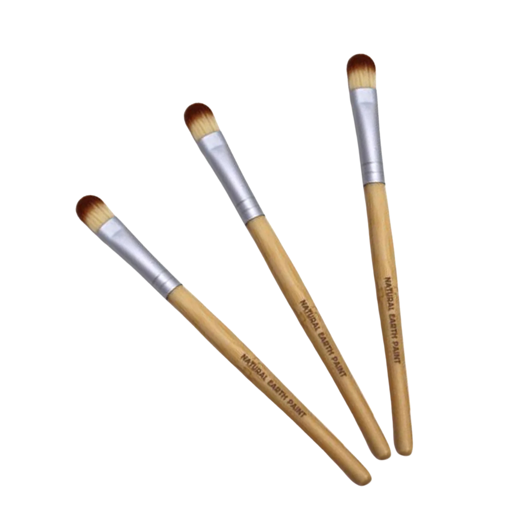 Three makeup brushes with wooden handles and silver ferrules on a white background