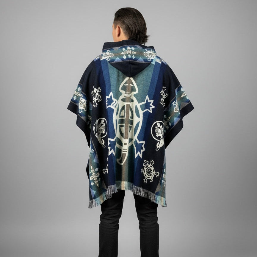 A person shown from the back wearing a dark navy hooded poncho with a large central fish motif and white, gray, and light blue decorative patterns, photographed against a plain light gray studio background.
