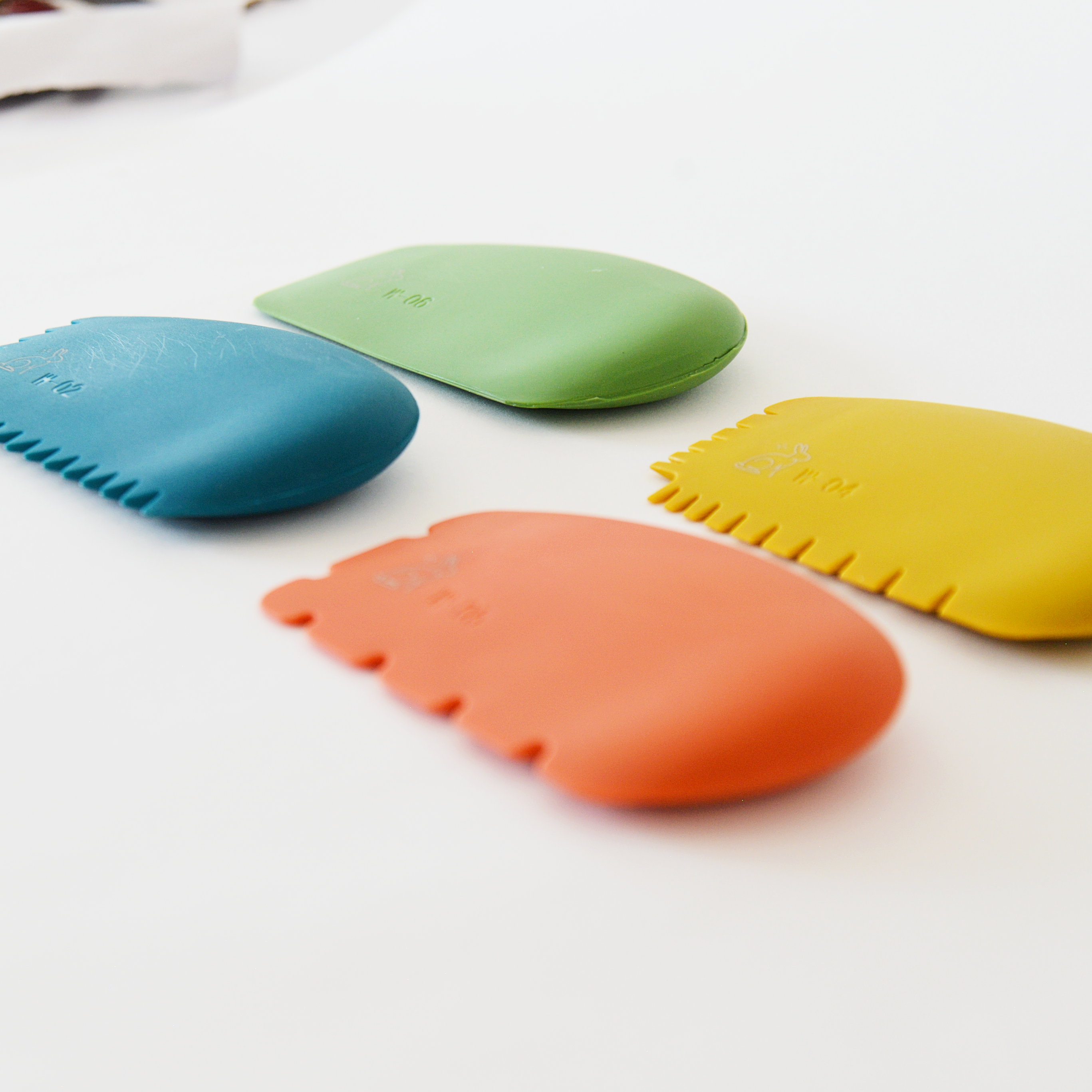 Four colorful silicone painting wedges on a white surface