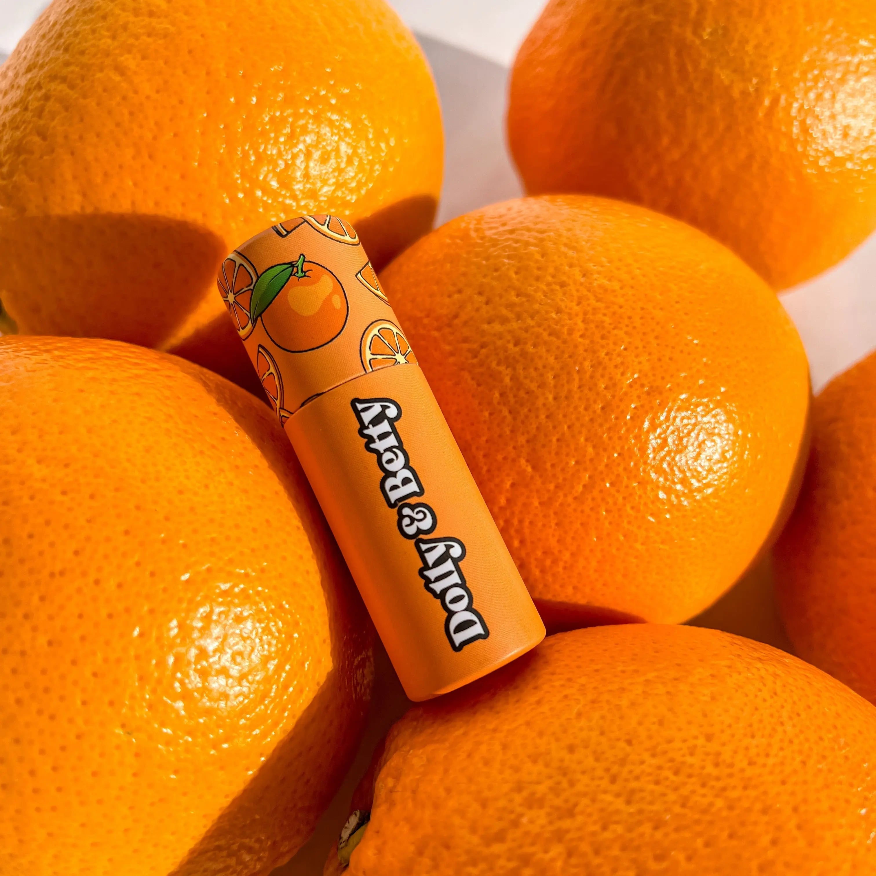 Lip balm with orange design surrounded by oranges