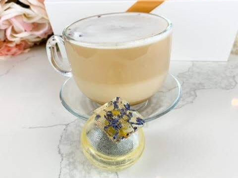 Luxurious London Fog tea bomb beside a frothy cup of tea, showcasing elegant gift packaging with dried lavender and sugar shell.