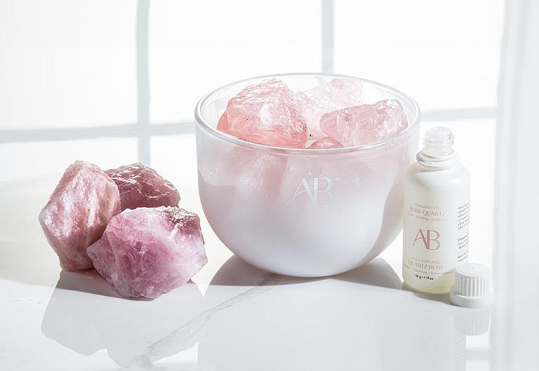 AB rose quartz crystal room fragrance bowl and oil with 'AP' branding on a light surface.
