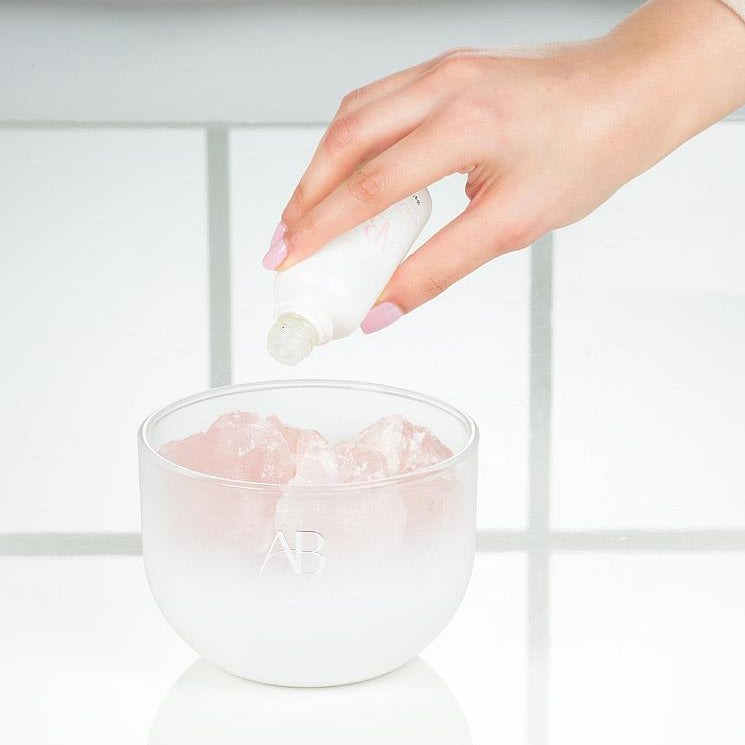 Hand applying AB rose quartz crystal room fragrance with a blurred background