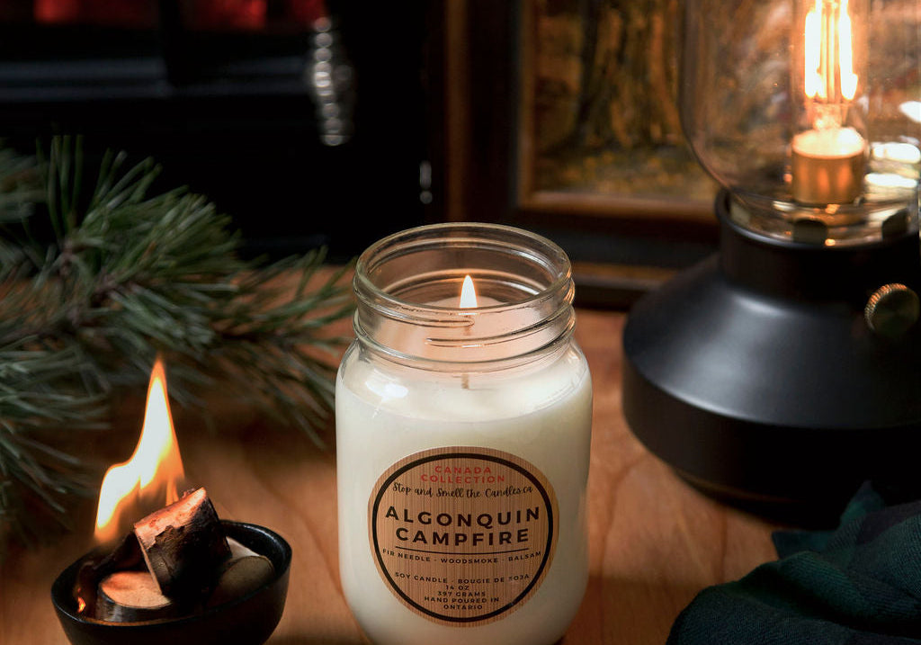 Candle with a label on a wooden surface next to a lantern and small candle from Stop and Smell the Candles