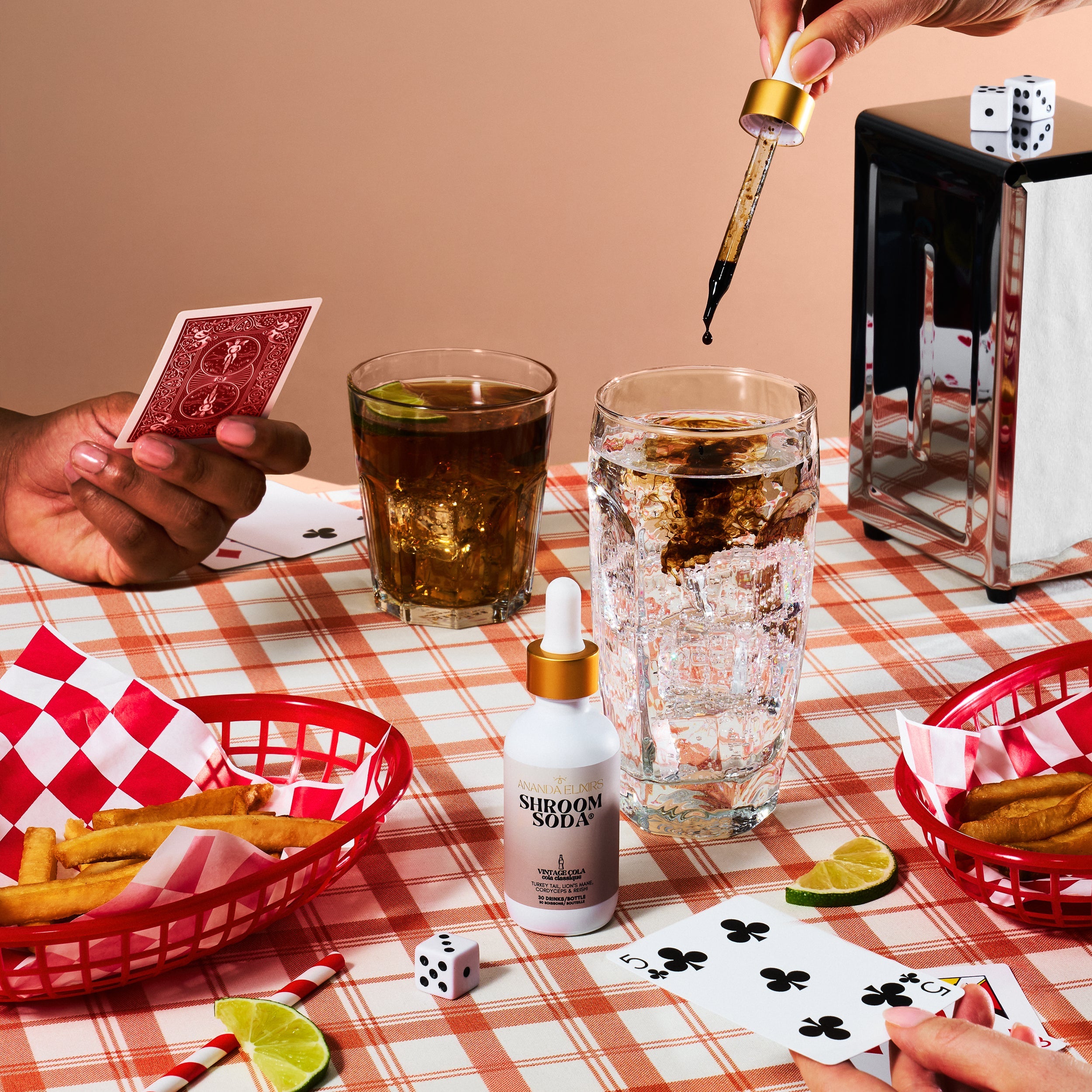 People playing cards at a table with drinks, snacks, and a dropper bottle.