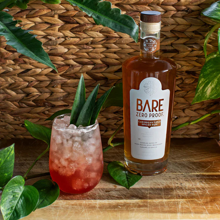 Bottle of Bare Zero Proof alcohol on a wooden surface with a cocktail and green leaves.  The Sobr Market