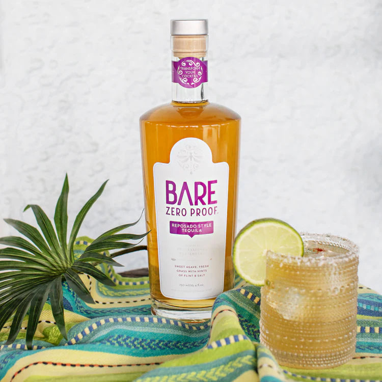 Bottle of Bare Zero Proof tequila with a glass of margarita on a colorful striped cloth.