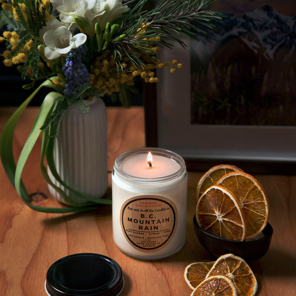 Candle with a label, dried oranges, and flowers on a wooden surface