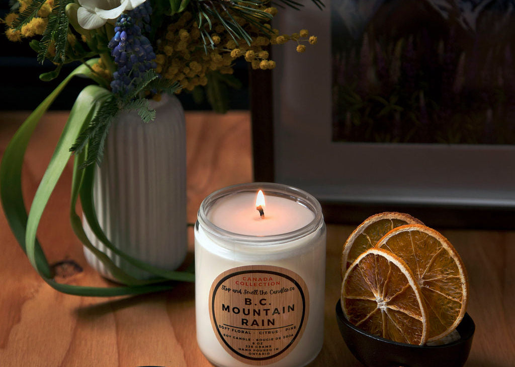 Candle with a label, dried oranges, and flowers on a wooden surface