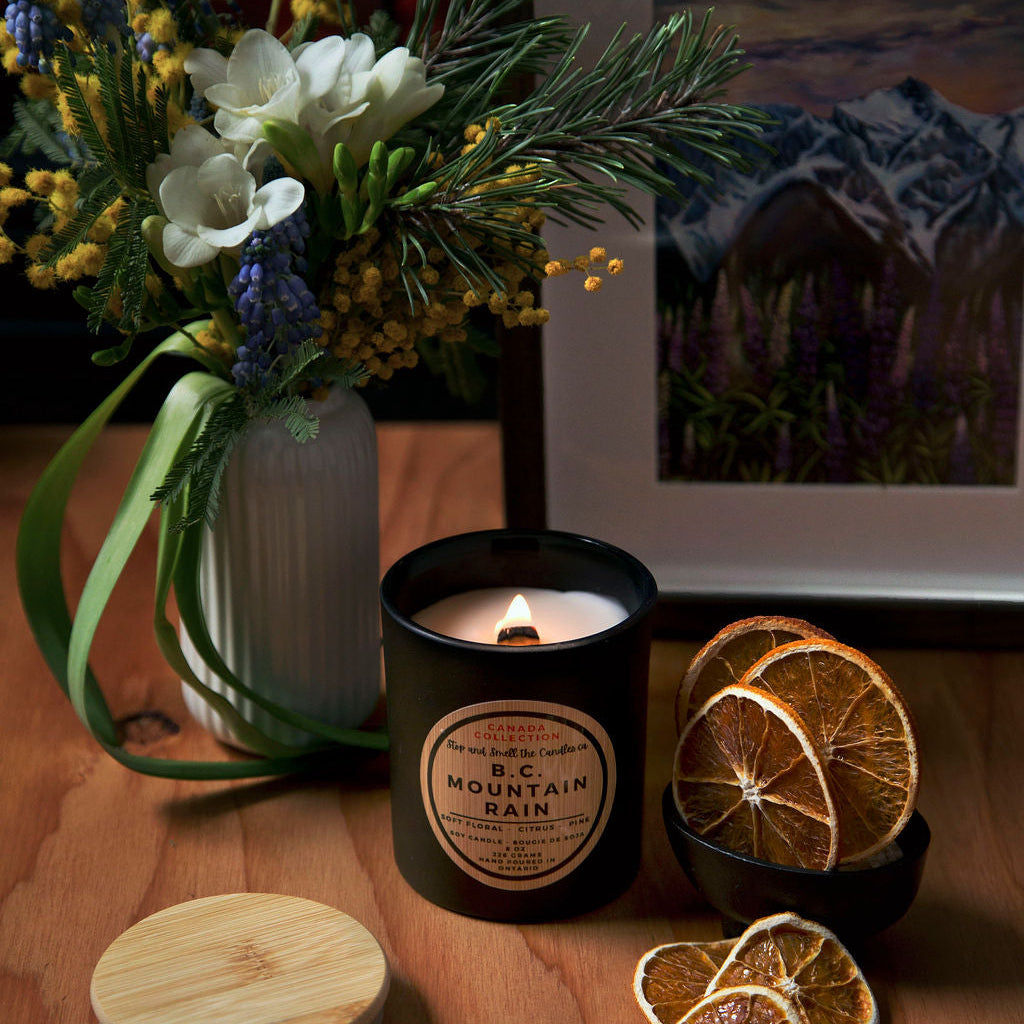 Stopandsmellthecandles BC Mountain Rain soy candle – 8 oz black jar with lit wooden wick, wooden lid, flowers and dried citrus