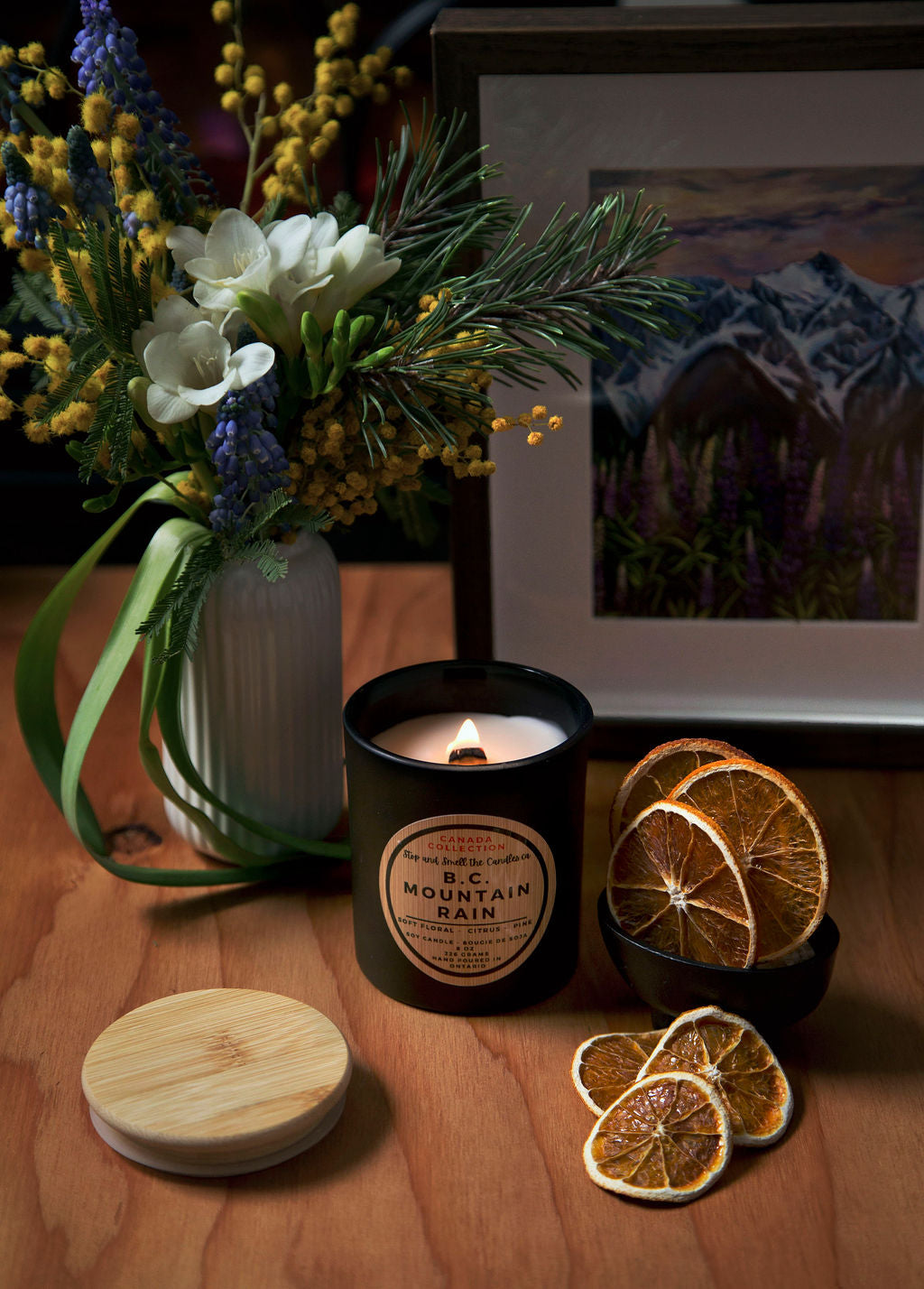 Stopandsmellthecandles BC Mountain Rain soy candle – 8 oz black jar with lit wooden wick, wooden lid, flowers and dried citrus